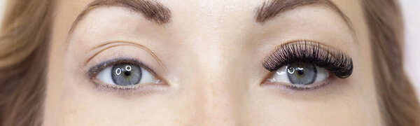 Eyelash extension procedure. Woman eye with long eyelashes. Close up