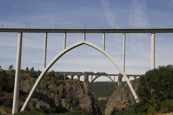 Container freight train crossing arch railroad bridge across Ulla river in Pontevedra, Spain