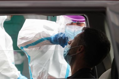 Bir Coruna-İspanya -18 Ağustos 2020: Bir sağlık çalışanı, Covid-19 'un varlığını veya yokluğunu belirlemek için bir arabanın içindeki bir kişi üzerinde PCR testi (ağız ve burun temizleme bezi) kullanır..