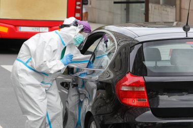 Bir Coruna-İspanya -18 Ağustos 2020: Bir sağlık çalışanı, Covid-19 'un varlığını veya yokluğunu belirlemek için bir arabanın içindeki bir kişi üzerinde PCR testi (ağız ve burun temizleme bezi) kullanır..