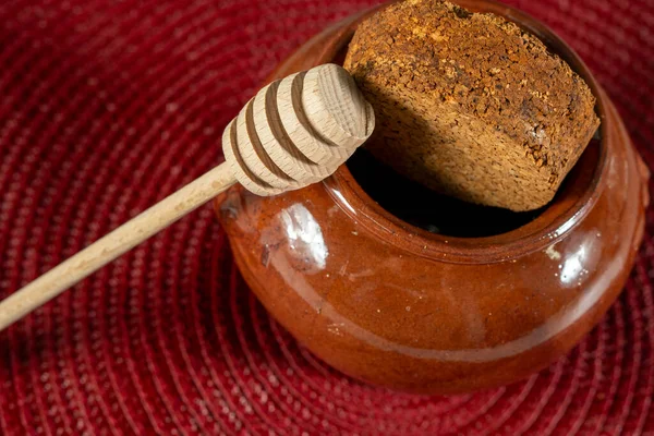 Tahta kaşık bal kavanozunun yanındadır. Kavanoz ekmek kırıntılarıyla dolu.