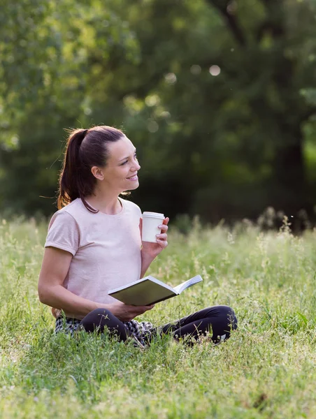 Młoda Kobieta Siedzi Trawie Parku Czytanie Książki Picia Kawy Cieszyć — Zdjęcie stockowe