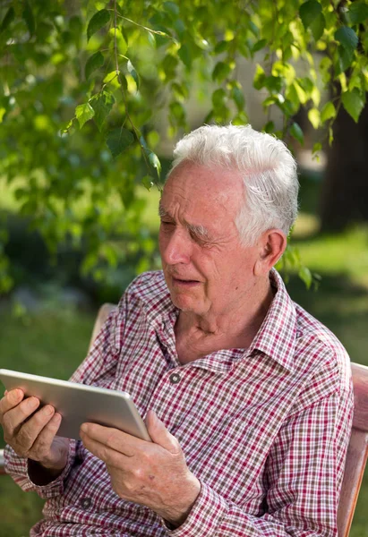 Sorgliga Senior Man Sitter Bänken Trädgården Tittar Tablett Och Gråter — Stockfoto