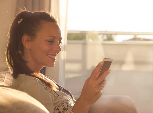 Menina Bonita Digitando Smartphone Sofá Com Bela Luz Sol Vindo — Fotografia de Stock