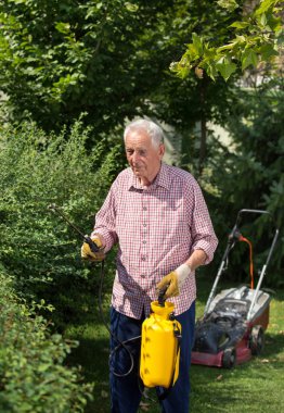 Bahçe Çit püskürtme komuta sizde. Arka planda biçme makinesi. Bitkiler kavramı dikkat çekici