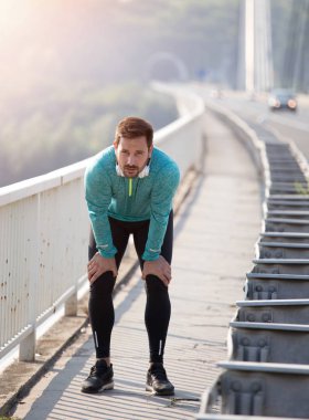 Yakışıklı adam köprüde koşu sonra dinlenme spor giyim