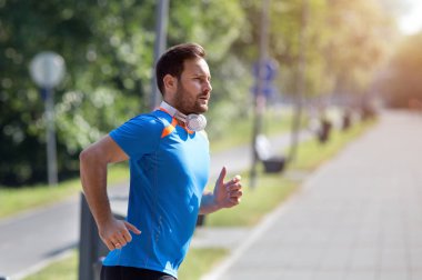 Parkta koşan memnun yakışıklı adam. Kentsel sabah koşu