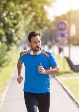 Parkta koşan memnun yakışıklı adam. Kentsel sabah koşu