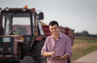 Tablet konumu traktör römork alanı ile önünde olan yakışıklı bir çiftçi