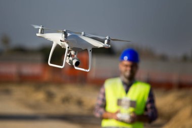 Uzaktan kumanda ile arka planda mevcuttur ve inşaat işçisi binasında uçan dronun yakın çekim