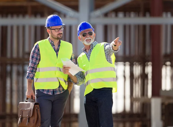 Zwei Ingenieure Mit Helmen Und Westen Unterhalten Sich Auf Einer — Stockfoto