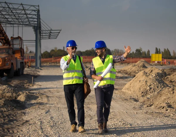 Dois Engenheiros Com Capacetes Coletes Conversando Canteiro Obras Frente Construção — Fotografia de Stock
