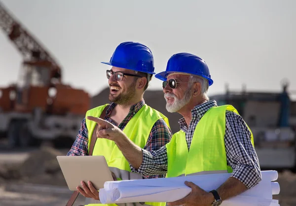 Twp Zufriedene Ingenieure Baustellengespräch Mit Baumaschinen Hintergrund — Stockfoto