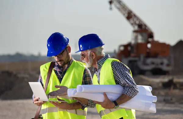 Zwei Ingenieure Betrachten Laptop Auf Baustelle Mit Baumaschinen Hintergrund — Stockfoto