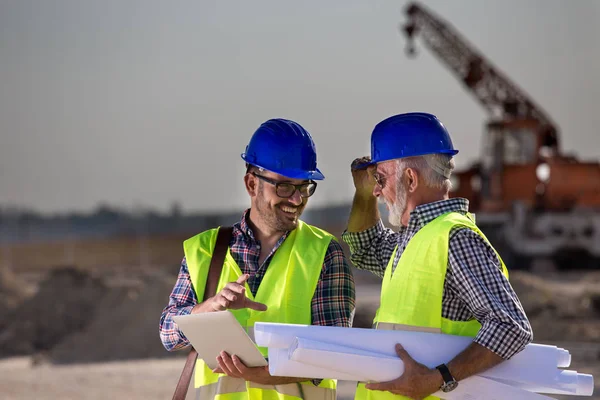 Twee Tevreden Ingenieurs Praten Bouwplaats Met Bouwmachines Achtergrond — Stockfoto