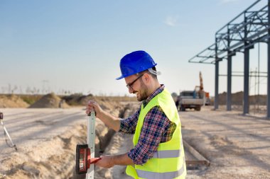 Site bina üzerinde kesici takımlar için ölçme lazer holding inşaat işçisi