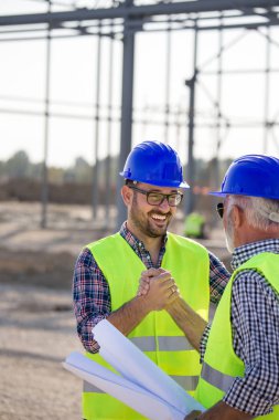İki el ile arka planda metal konstrüksiyon site bina mühendisler