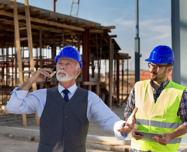 Wütender Senior Ingenieur Mit Helm Telefoniert Neben Jungem Arbeiter Auf — Stockfoto