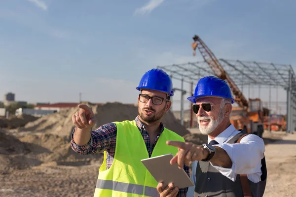 Zwei Zufriedene Ingenieure Gespräch Auf Der Baustelle Mit Baustruktur Hintergrund — Stockfoto