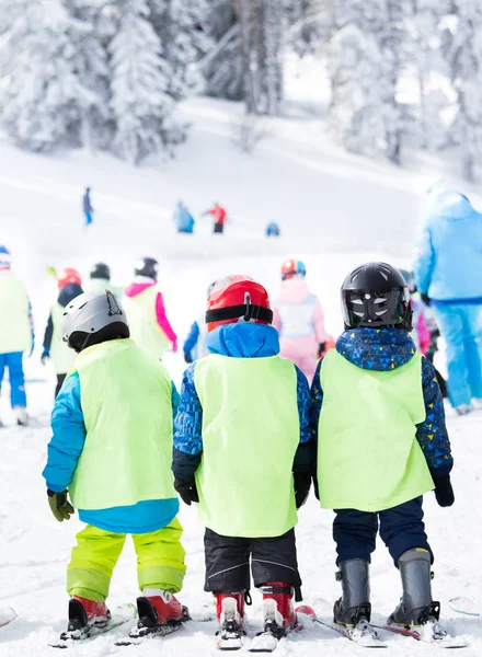 一群戴着头盔和背心的小孩子们站在滑雪板上 学习在多边形上滑雪的基本技巧 — 图库照片