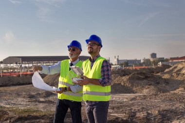 Kask ve drone ile uzaktan kumanda ile işletim ve gökte ararken yelekler ile iki mühendis. İnşaat sektöründe teknoloji yenilikleri