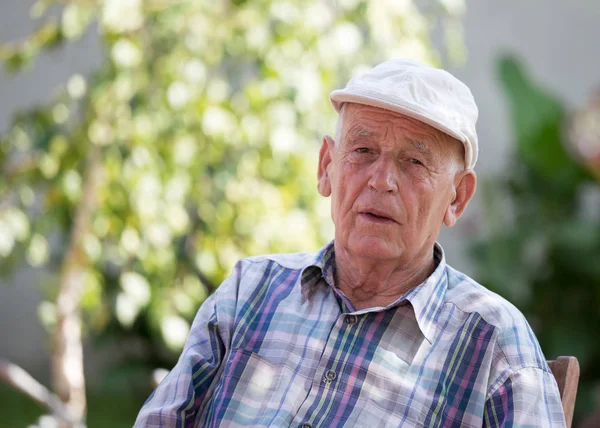 Retrato Homem Sênior Com Boné Sentado Parque Com Árvore Verde — Fotografia de Stock