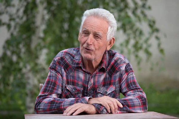 Smilling Oude Man Zit Aan Tafel Tuin — Stockfoto