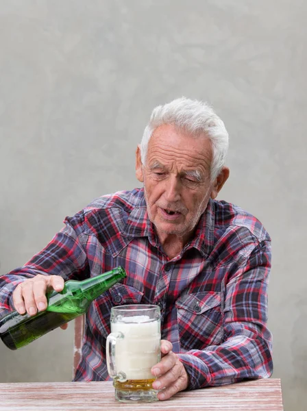 坐在桌旁喝啤酒的醉酒老人 — 图库照片