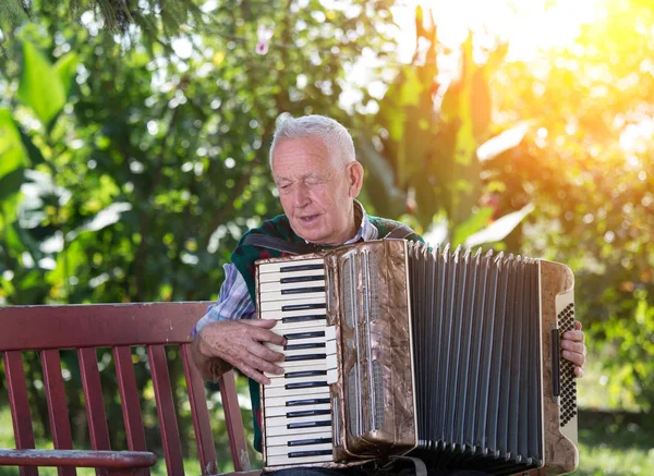 高齢男性の庭のベンチにアコーディオンを演奏 — ストック写真
