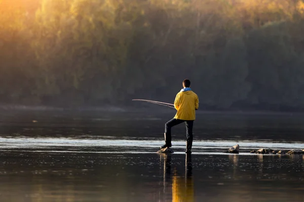 寒い朝に川沿岸で釣りの若い男の後姿 — ストック写真