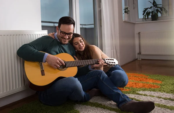 Feliz Casal Sentado Chão Lado Radiador Janela Tocando Guitarra — Fotografia de Stock