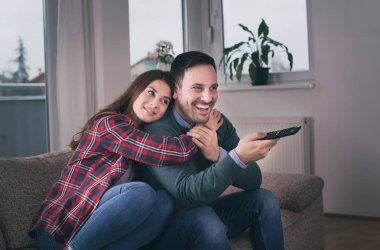 Evde kanepede televizyon izlerken mutlu genç çift