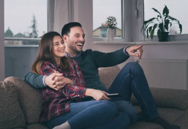 Evde kanepede televizyon izlerken mutlu genç çift
