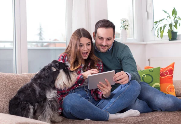 Feliz Jovem Casal Sentado Sofá Com Cão Olhando Para Tablet — Fotografia de Stock