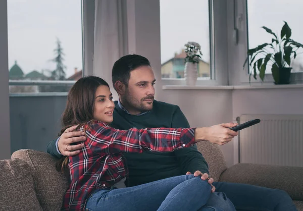 Genç çift evde TV izliyor. Uzaktan kumanda ile bıkkın duygu adam neşeli bir kızdır