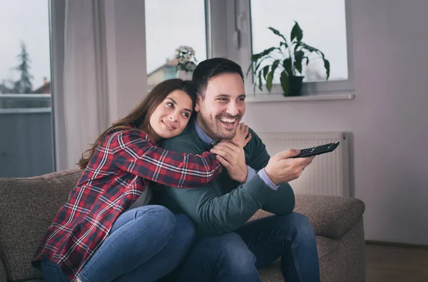 Evde kanepede televizyon izlerken mutlu genç çift