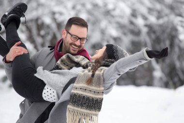 Üzerinde zevk mutlu gülümseyen çift ormanda kar. Beyaz ağaçların önünde kaldırma kız adam