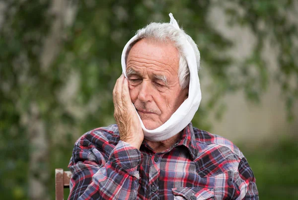 歯痛を持つ老人に冷たい布で頭をバインド — ストック写真