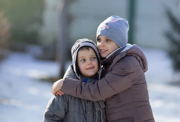 Kinder umarmen sich im Schnee — Stockfoto