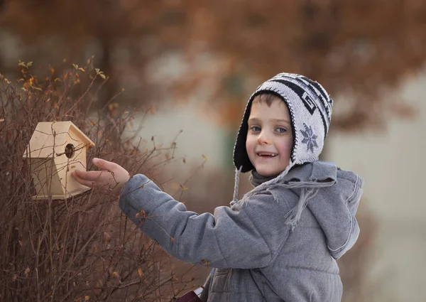 Niño con casa de aves en la nieve —  Fotos de Stock