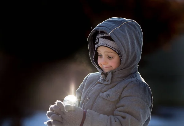 Junge mit magischer Lichtkugel auf Schnee — Stockfoto