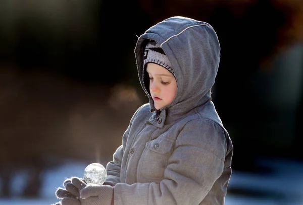 Chlapec s kouzelnou světelnou koulí na sněhu — Stock fotografie