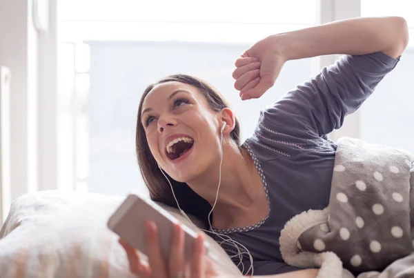 Menina ouvindo música e cantando na cama — Fotografia de Stock