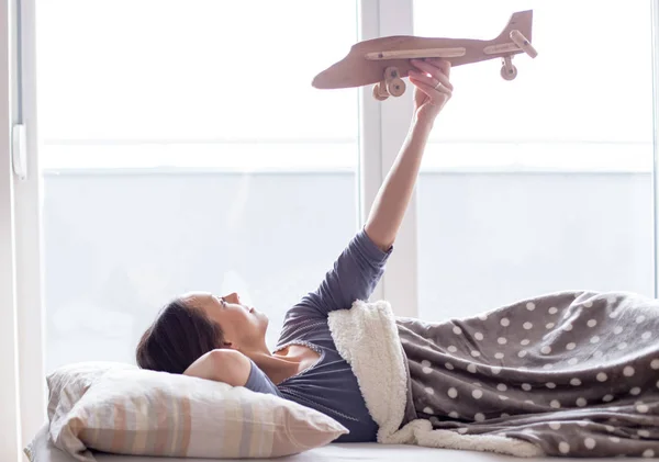 Девушка в постели с игрушкой для самолета и мечтами — стоковое фото