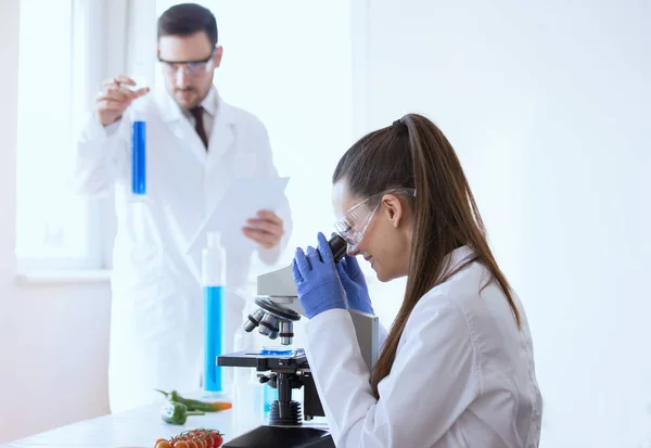 Scienziati con verdure in laboratorio — Foto Stock