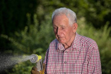 Bahçede yaşlı adam sulama bitkileri