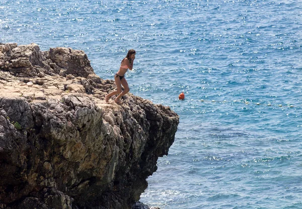 Mädchen springt von Klippe ins Wasser Stockbild