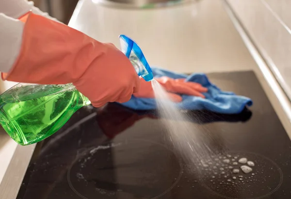 Vrouw schoonmaken inductiekachel in keuken — Stockfoto