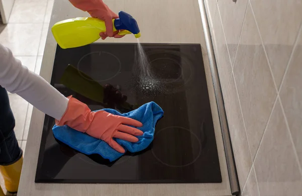 Woman cleaning induction stove in kitchen — Stock Photo, Image