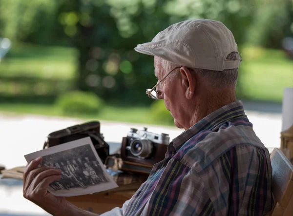 Старший мужчина смотрит на старые фотографии — стоковое фото